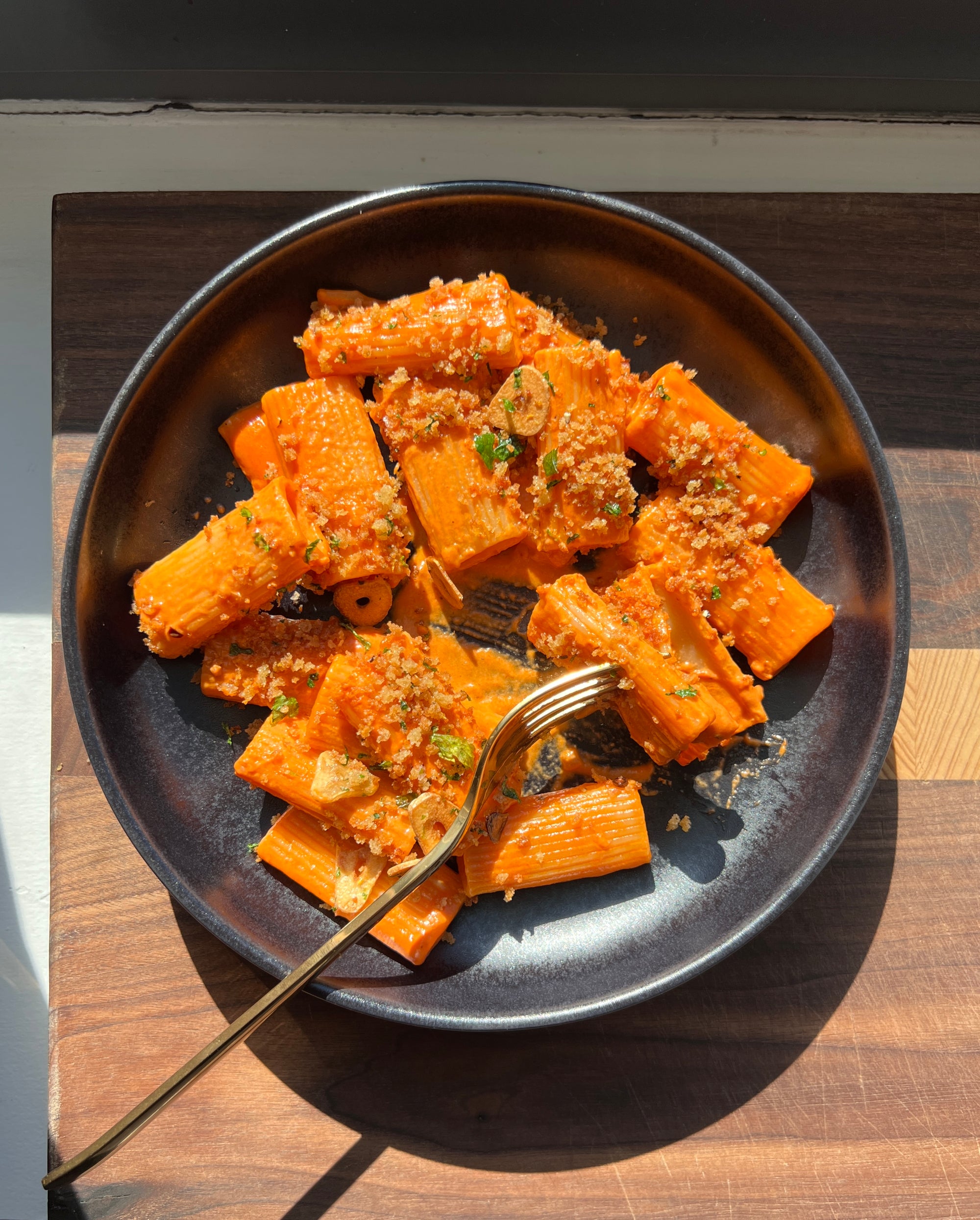 a bowl of vodka sauce rigatoni pasta with crispy garlic breadcrumbs on top.