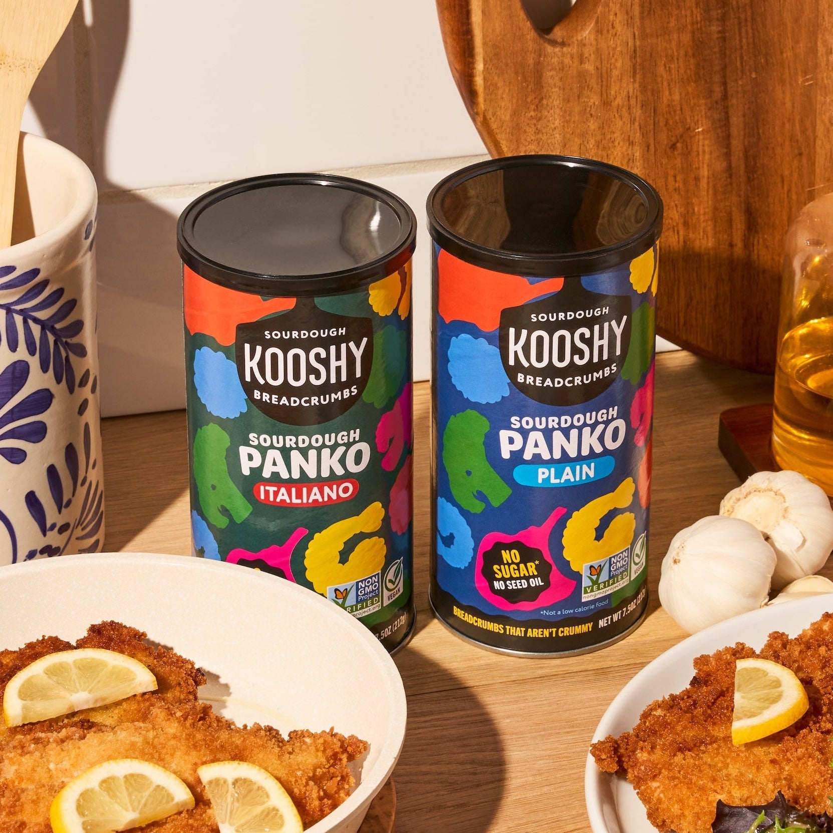 Dinner setup with breaded dishes, salad, and Kooshy Panko products on a wooden table.