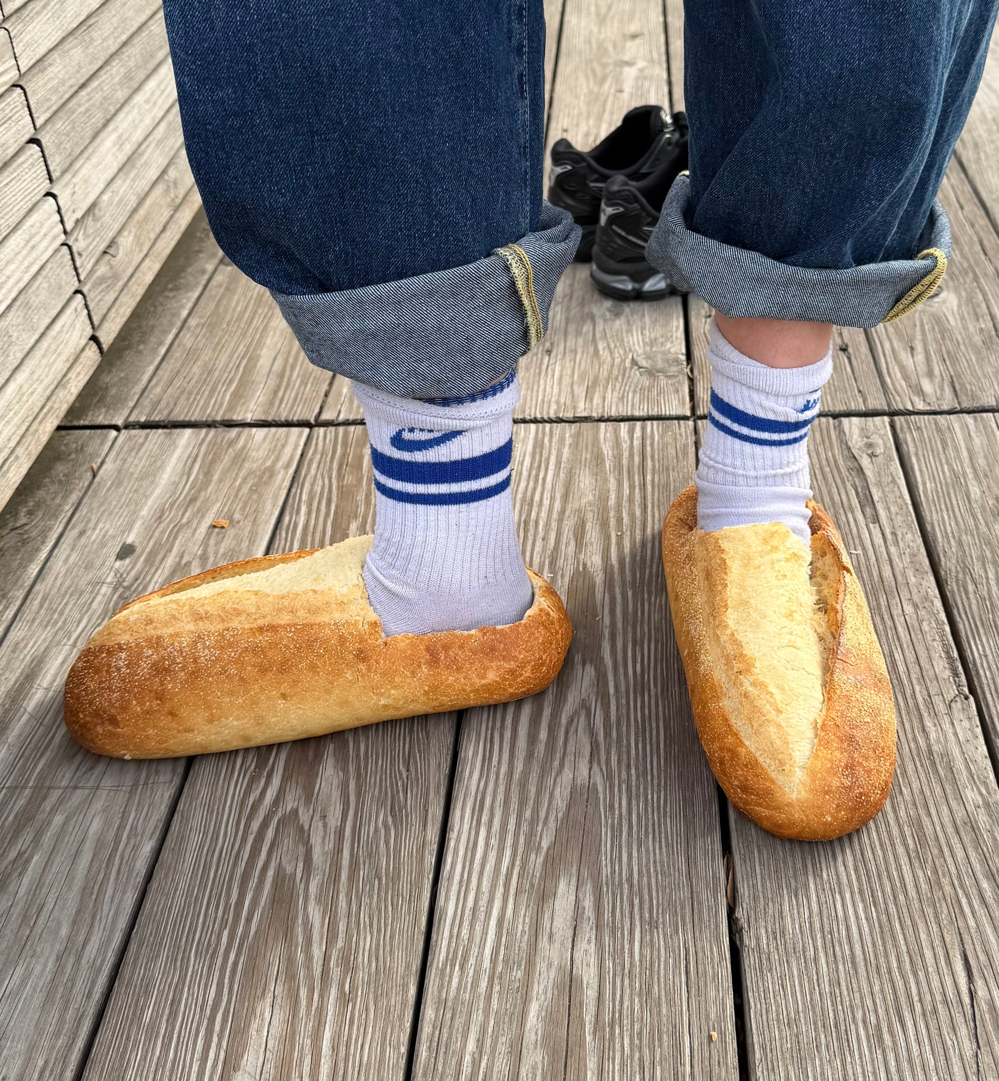 Person wearing bread-shaped shoes on a wooden floor