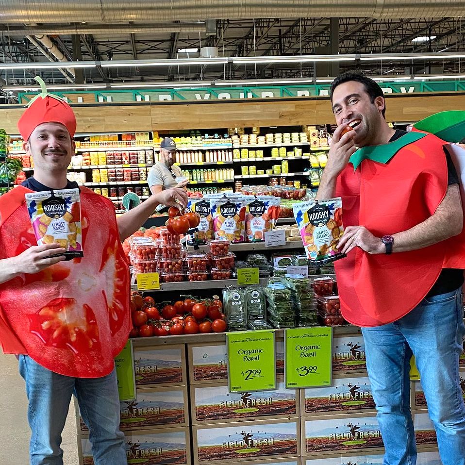 Image shows two founders wearing tomato costumes at Whole Foods.